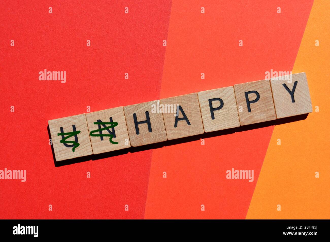 Unglücklich, Wort in 3d-Holz Alphabet Buchstaben mit Präfix un durchgestrichen, so dass das Wort glücklich Stockfoto