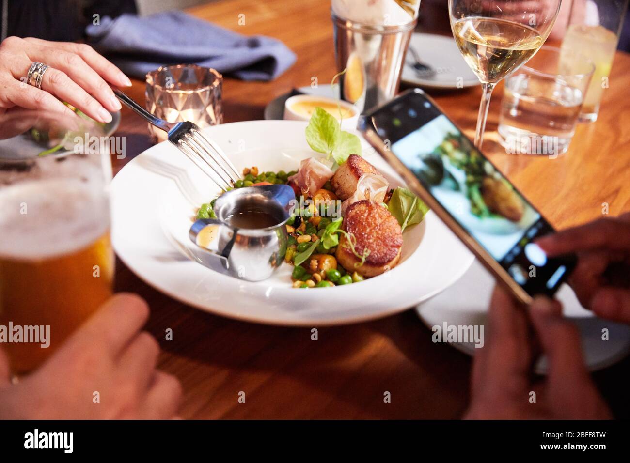 Eine Foodie macht vor dem Essen ein Foto von ihrer Mahlzeit für soziale Medien Stockfoto
