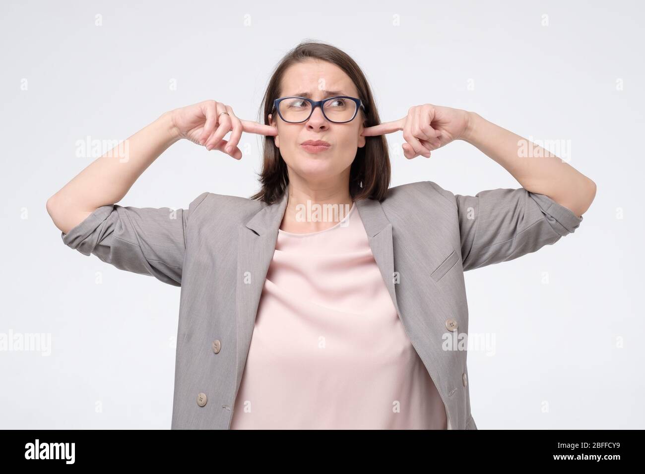 Reife Frau in Brille mit Unzufriedenheit Blick verstopft ihre Ohren mit Lärm wollen Stille und ruhige Atmosphäre erschöpft ärgerlich Stockfoto