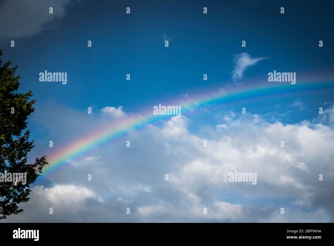 Regenbogen vor blauem Himmel mit Wolken Stockfoto