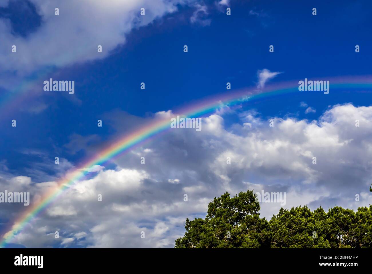 Regenbogen vor blauem Himmel mit Wolken Stockfoto