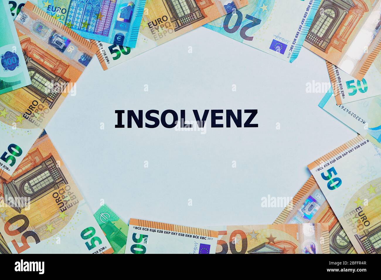 Das deutsche Wort für Insolvenz ist auf einem Weißbuch gedruckt, um liegen viele verschiedene Euro-Banknoten Stockfoto
