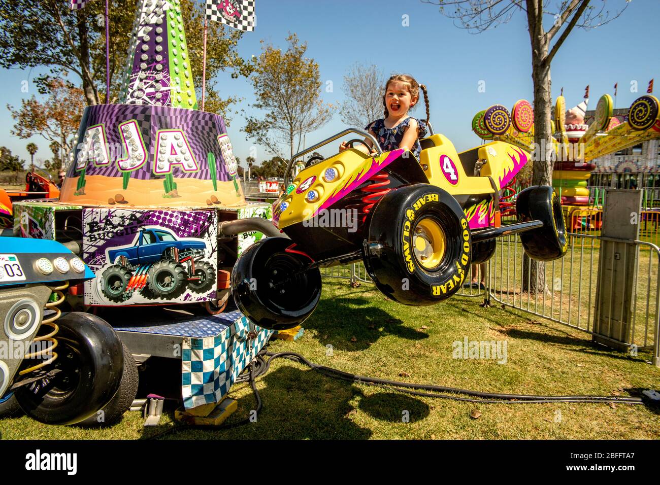 Ein glückliches vierjähriges Mädchen genießt die autoähnliche Baja Buggies in einem Park in Costa Mesa, CA. Stockfoto