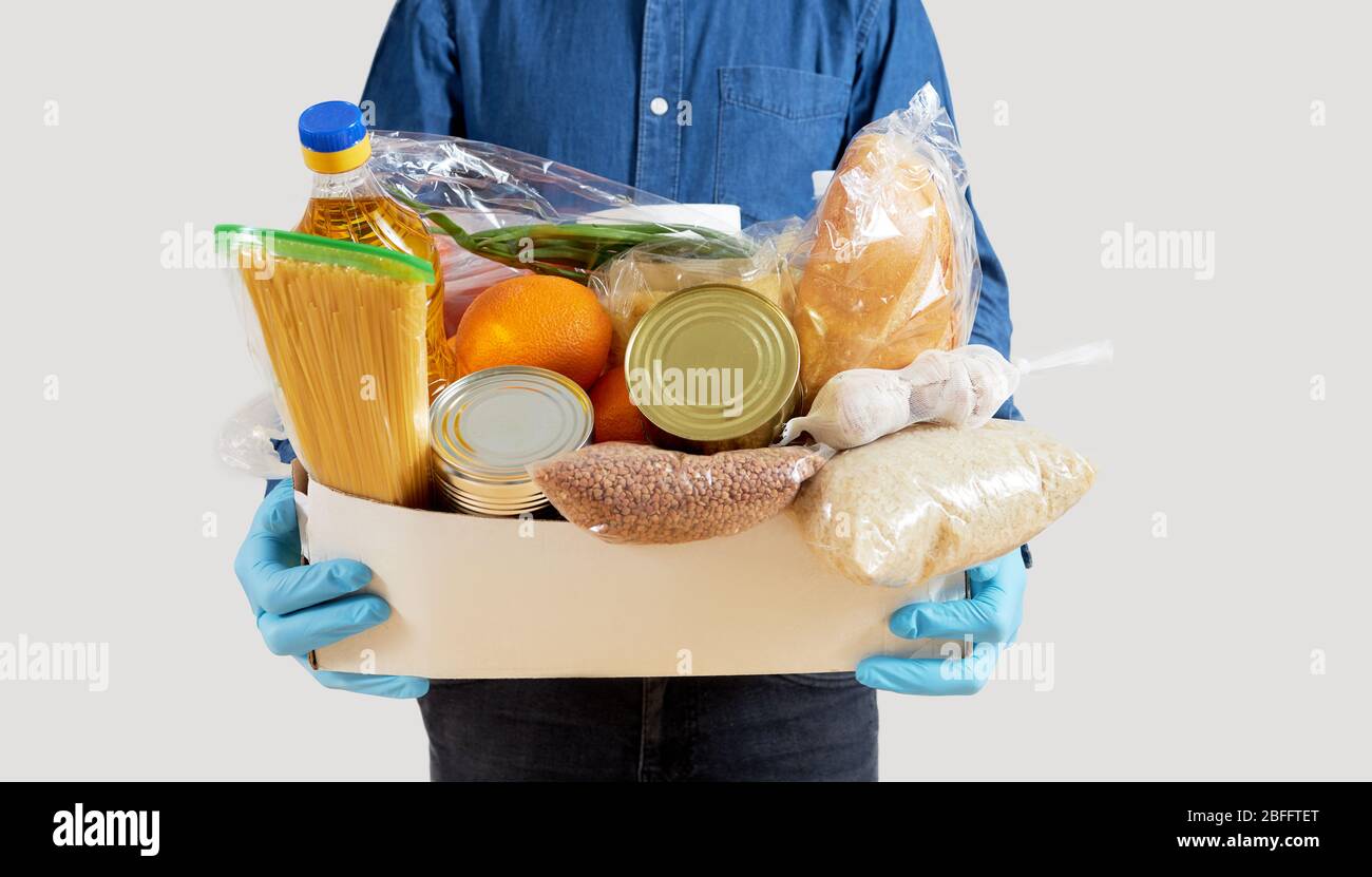 Herren Hände halten Quarantäne Spende Box. Lebensmittel, Kleidung und persönliche Schutzausrüstung. Konzept für die Lieferung von Lebensmitteln. Stockfoto