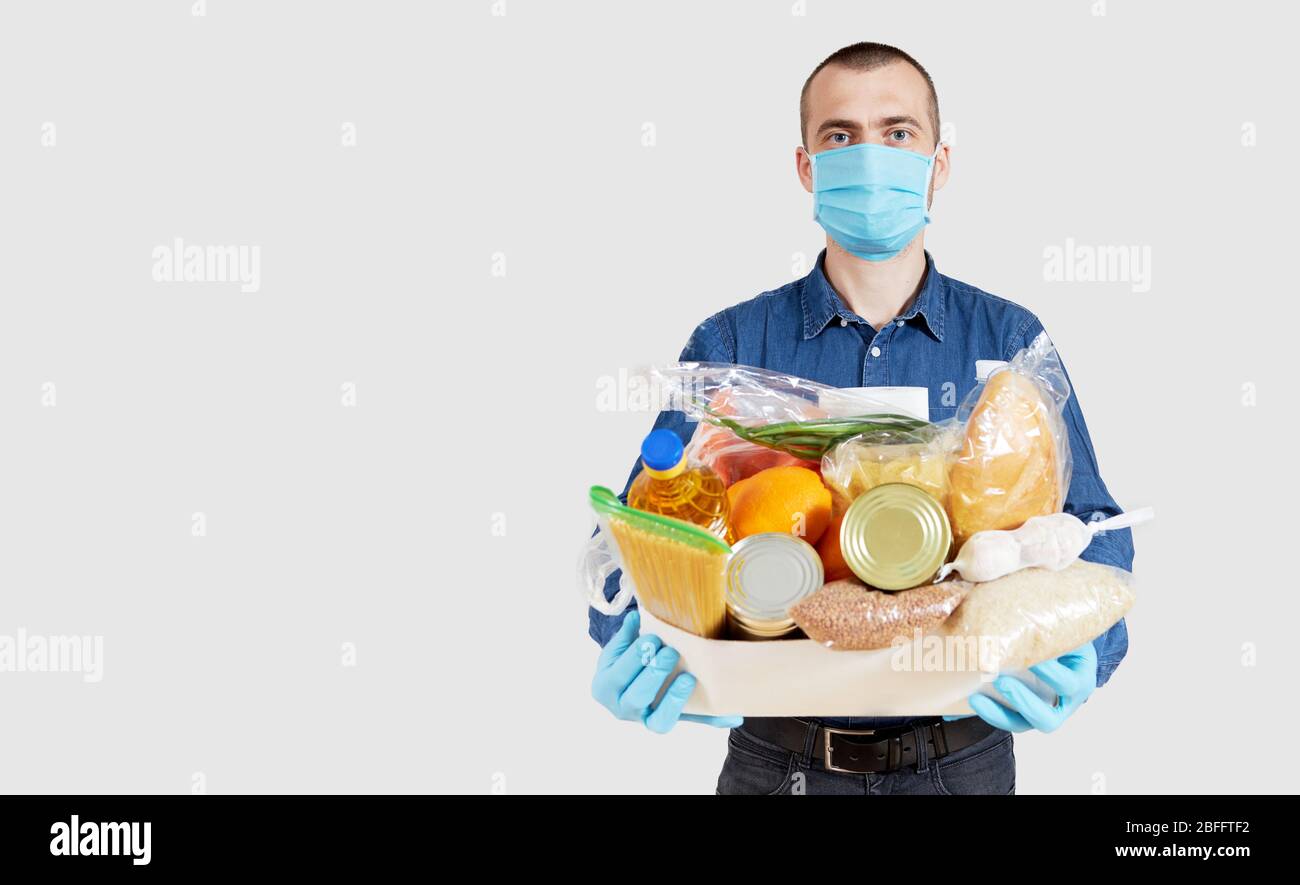 Herren Hände halten Quarantäne Spende Box. Lebensmittel, Kleidung und persönliche Schutzausrüstung. Konzept für die Lieferung von Lebensmitteln. Stockfoto