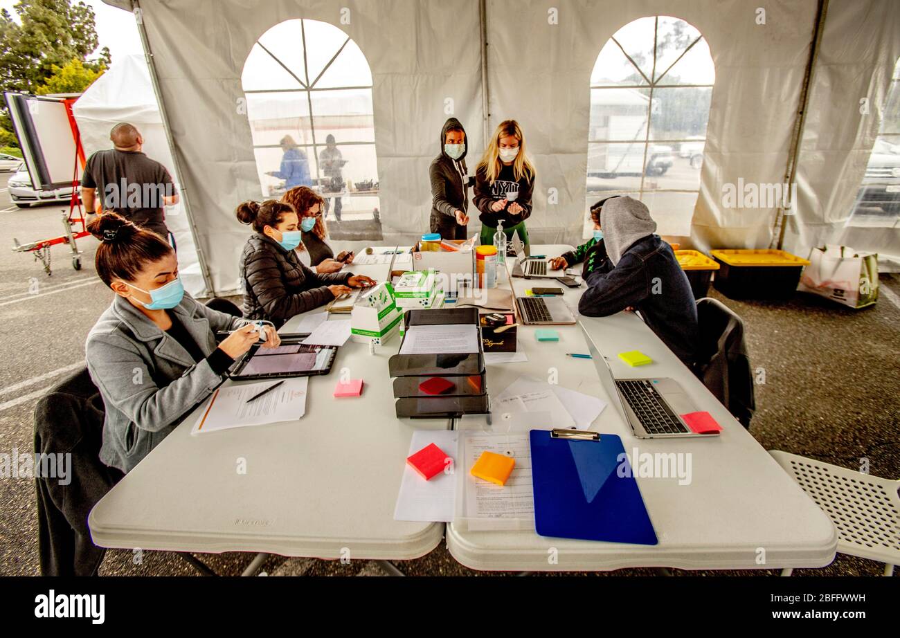 Die Krankenschwestern an Laptops tragen Sicherheitsmasken und Gummihandschuhe und koordinieren die Durchfahrt der Patienten in einer Bluttesteinrichtung für Coronavirus oder COVID-19 in einem Parkhaus in WSestminster, CA. Stockfoto