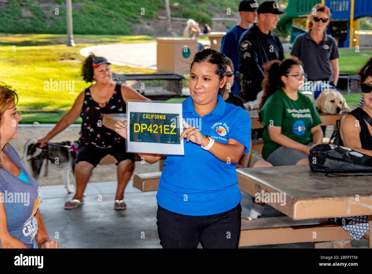 Ein Dozent der Polizeiabteilung erklärt den Einheimischen die Anerkennung von Kfz-Kennzeichen am Tatort, die an einem Vortrag über die zivilgesellschaftliche Verantwortung für Fußgänger in einem Park in Corona, CA, teilnehmen. Stockfoto