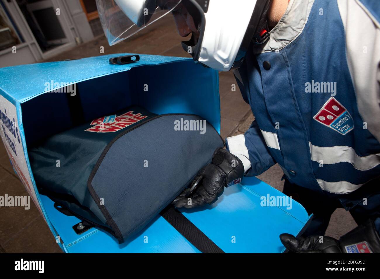 Ein Domino Pizza Auslieferungsfahrer Laden sein Moped mit frisch zubereiteten, heiße Pizza. Stockfoto