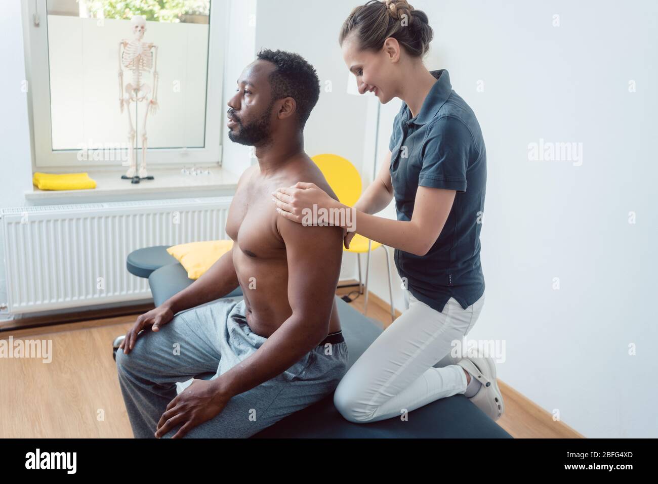 Physiotherapeuten massieren eine junge schwarze Mann auf die Schulter Stockfoto