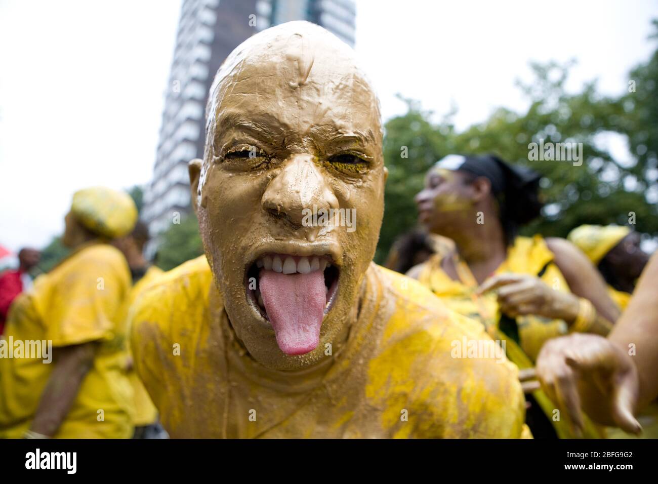 Während des Notting Hill Carnival in London ist das Gesicht der Tänzer mit gelber Farbe bedeckt Stockfoto