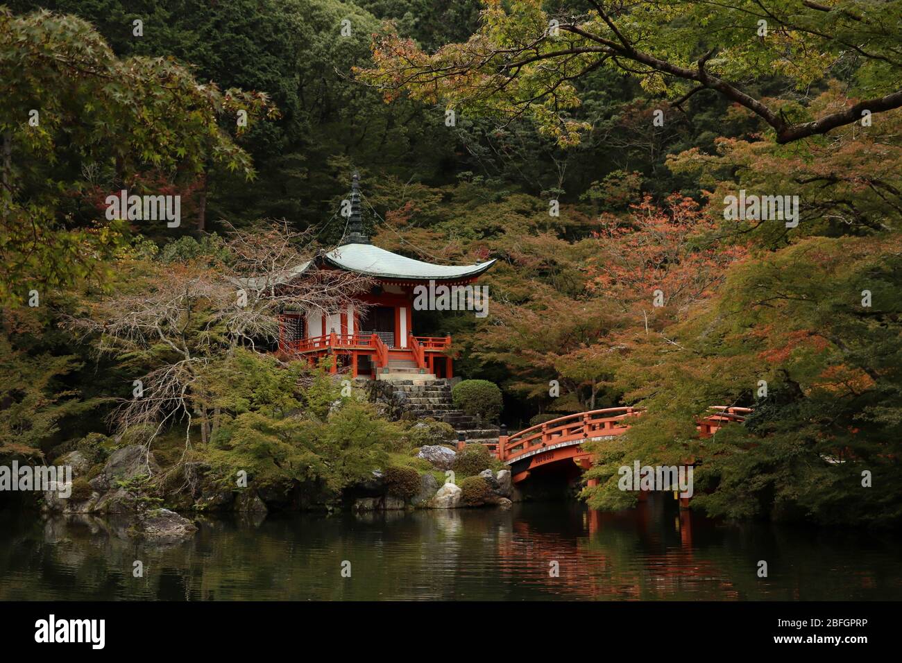 Blick über einen Teich zu Bentendo Hall mit einer Zinnoberbrücke am Daigo-ji Tempel in Daigo, Japan im frühen Herbst, umgeben von Laub. Stockfoto