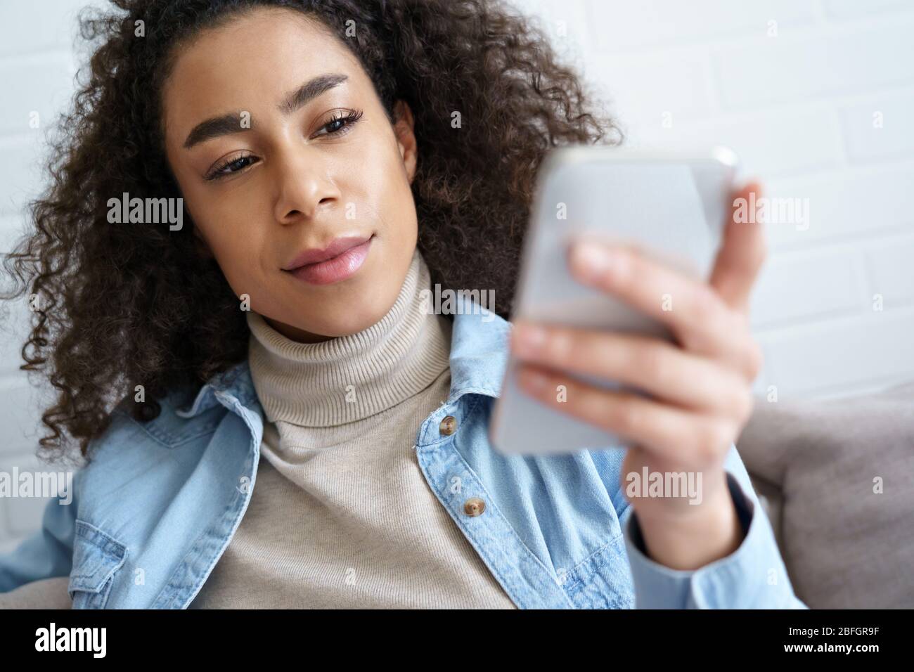 Junge afroamerikanische Frau Smartphone mit App zu Hause. Stockfoto