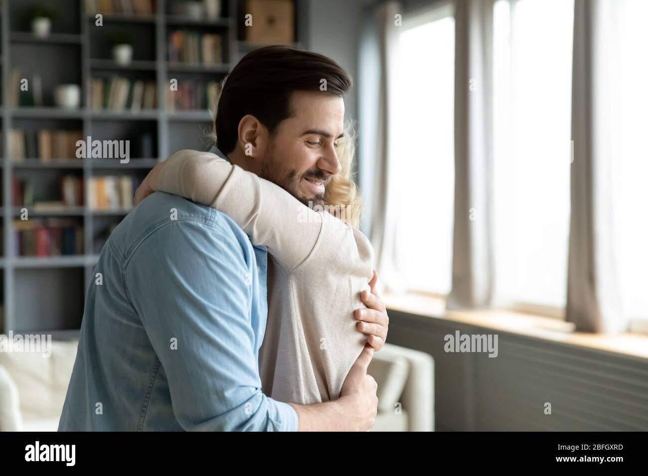 Erwachsener Sohn besuchte Mutter Menschen umarmend im Wohnzimmer stehen Stockfoto