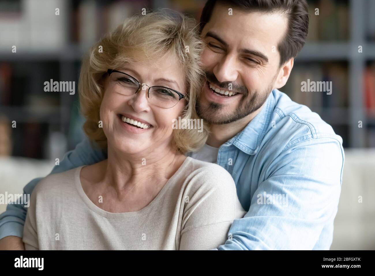 Erwachsene Sohn umarmt ältere Mutter lachen scherzend genießen Zeit zusammen Stockfoto