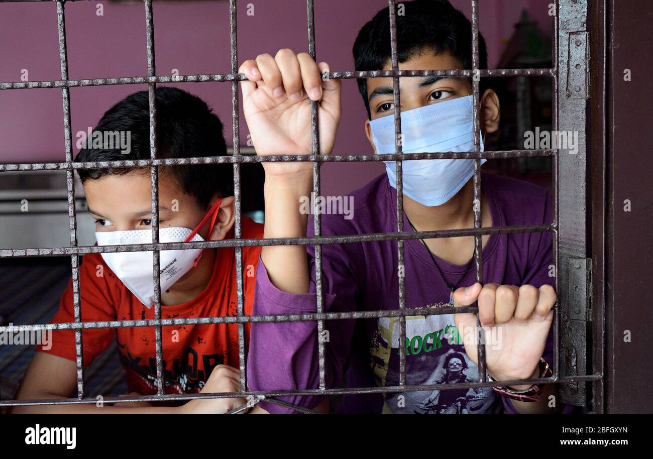 Besorgtes und ängstigendes Kind mit schützender Gesichtsmaske, das durch sein Zimmerfenster die verlassenen Straßen beobachtet - wegen Covit19 Coronavirus pandemi Stockfoto