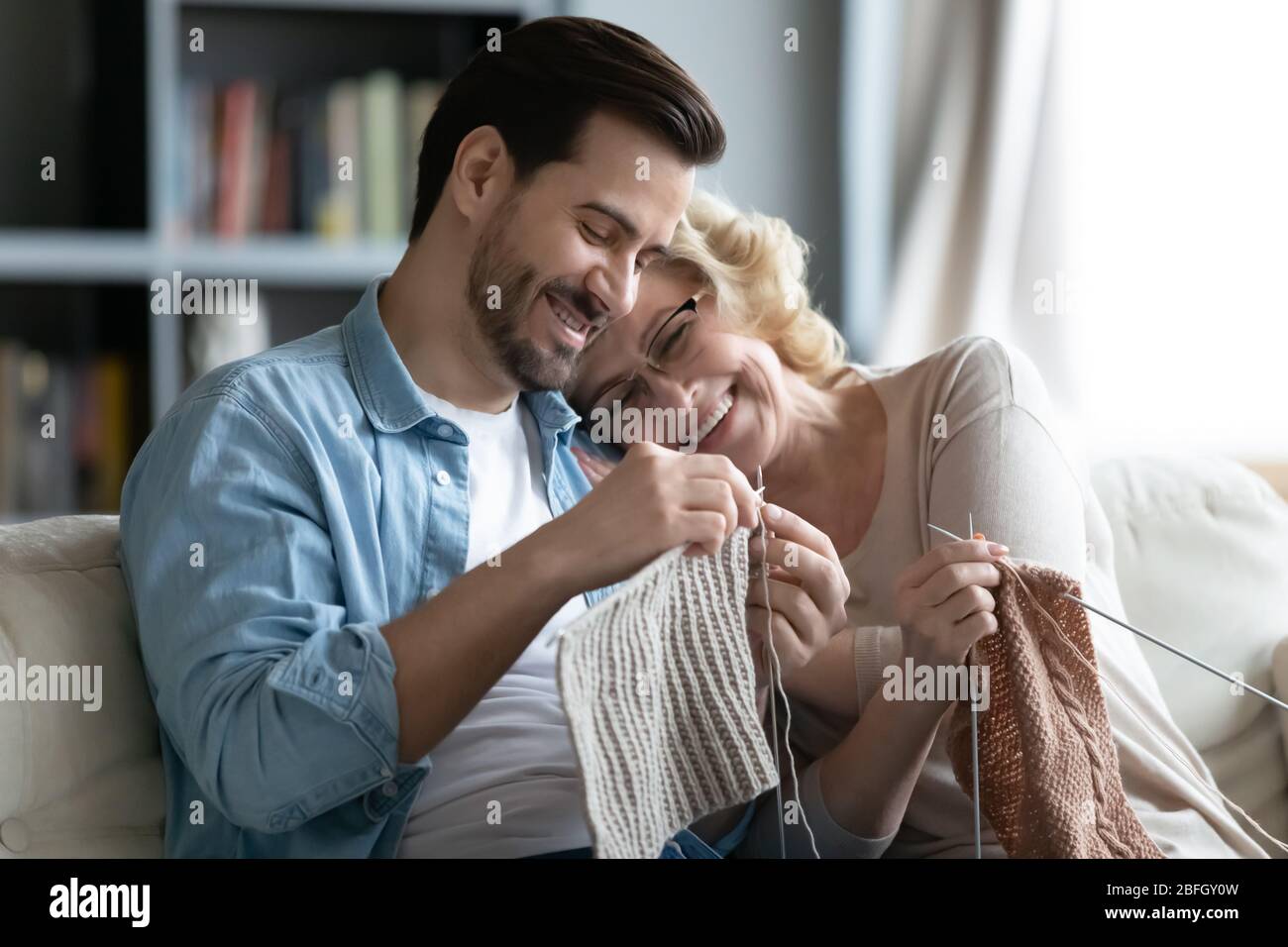 Alte Mutter und erwachsener Sohn Stricken verbringen Freizeit zusammen Stockfoto