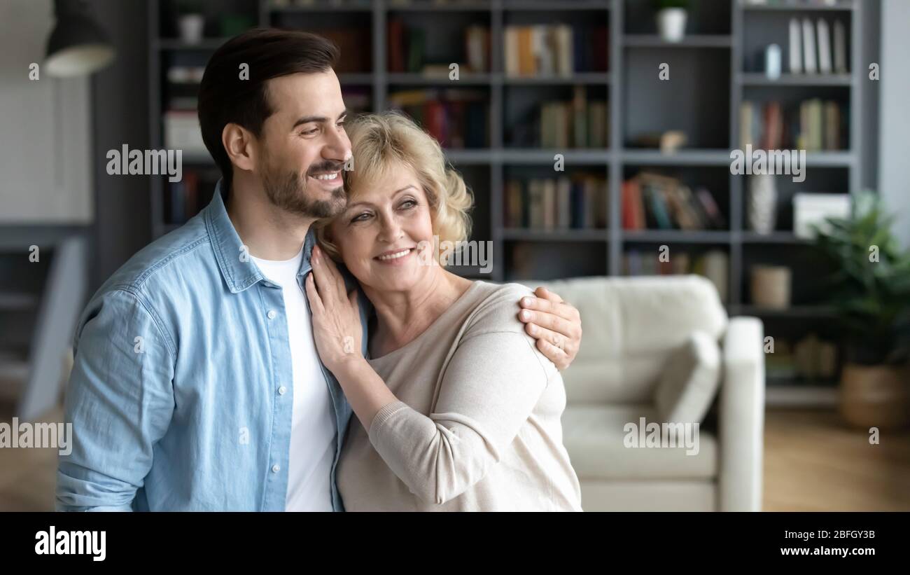 Innen von gemütlichen Zimmer umarmt gealterte Mutter und erwachsener Sohn Stockfoto