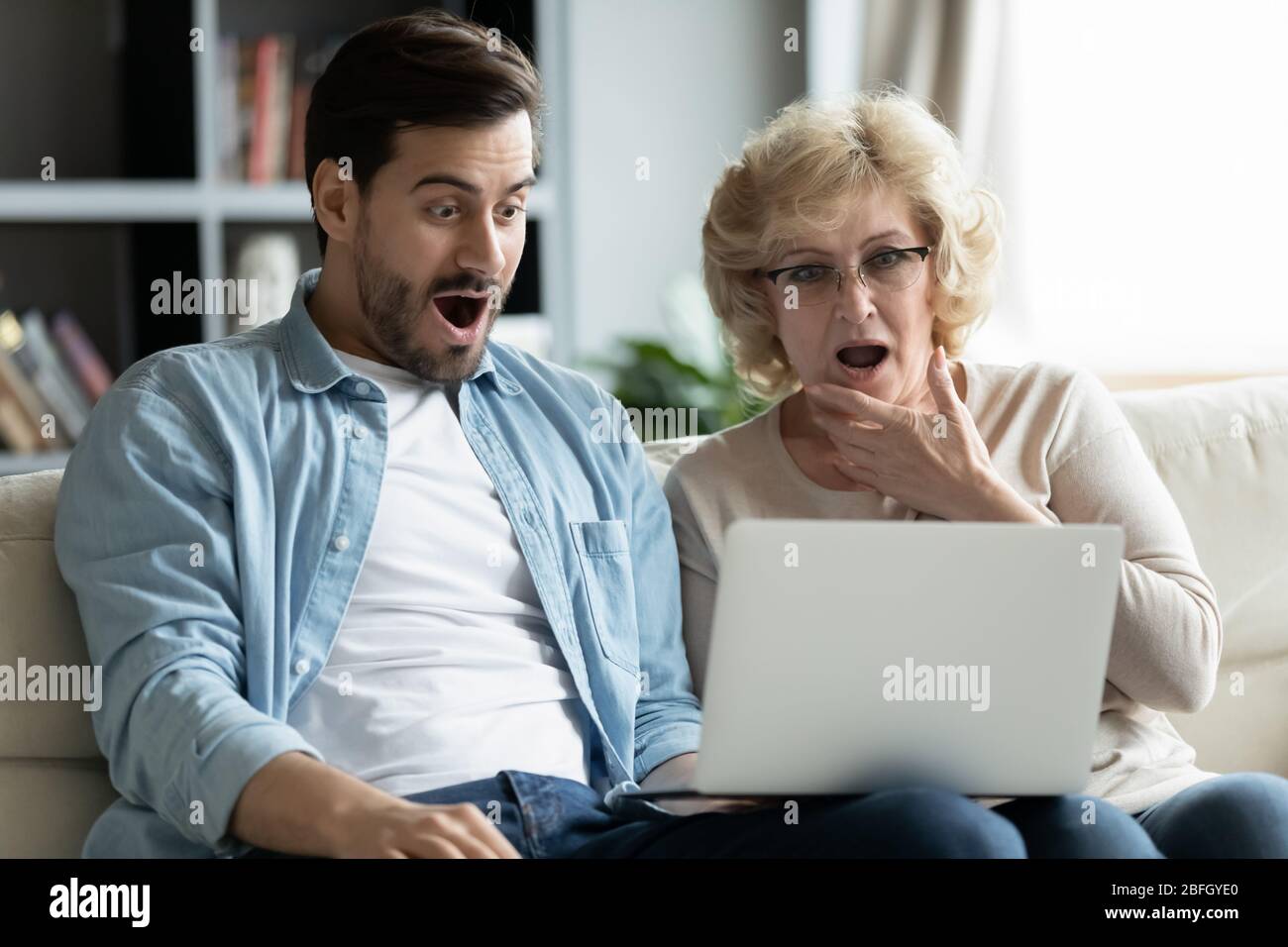 Erwachsene Sohn ältere Mutter Blick auf Laptop-Bildschirm fühlt sich schockiert Stockfoto
