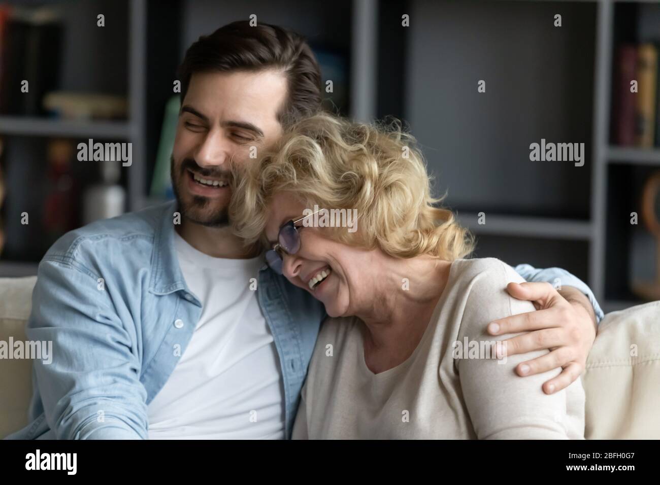 Erwachsene Sohn Umarmungen ältere Mutter Familie genießen sprechen lustige Unterhaltung Stockfoto