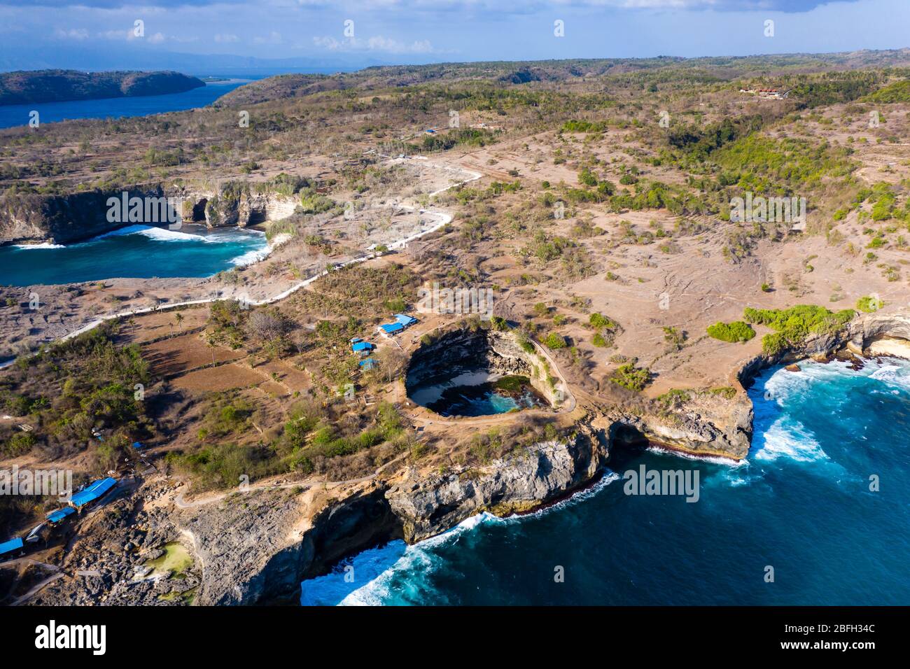 Luftaufnahme der Meereswellen, die durch einen Felsbogen in eine runde, isolierte Bucht stürzen (Broken Beach, Nusa Penida, Indonesien) Stockfoto