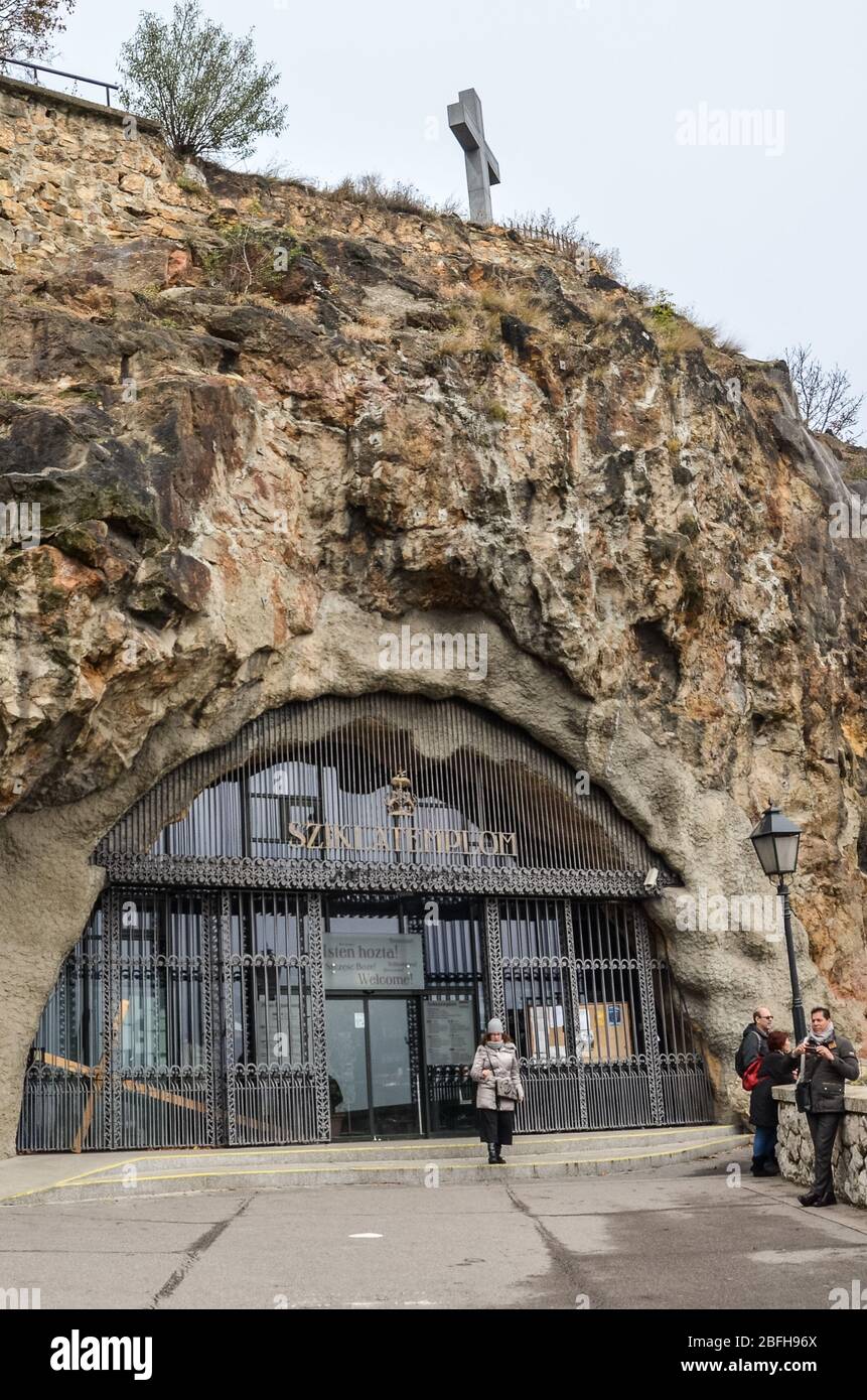 Budapest, Ungarn - 6. November 2019: Eingang zur Gellert Hill Cave Church, Sziklatemplom. Felsenkirche in der ungarischen Hauptstadt mit Menschen. Überqueren Sie die Spitze des Felsens. Vertikales Foto. Stockfoto