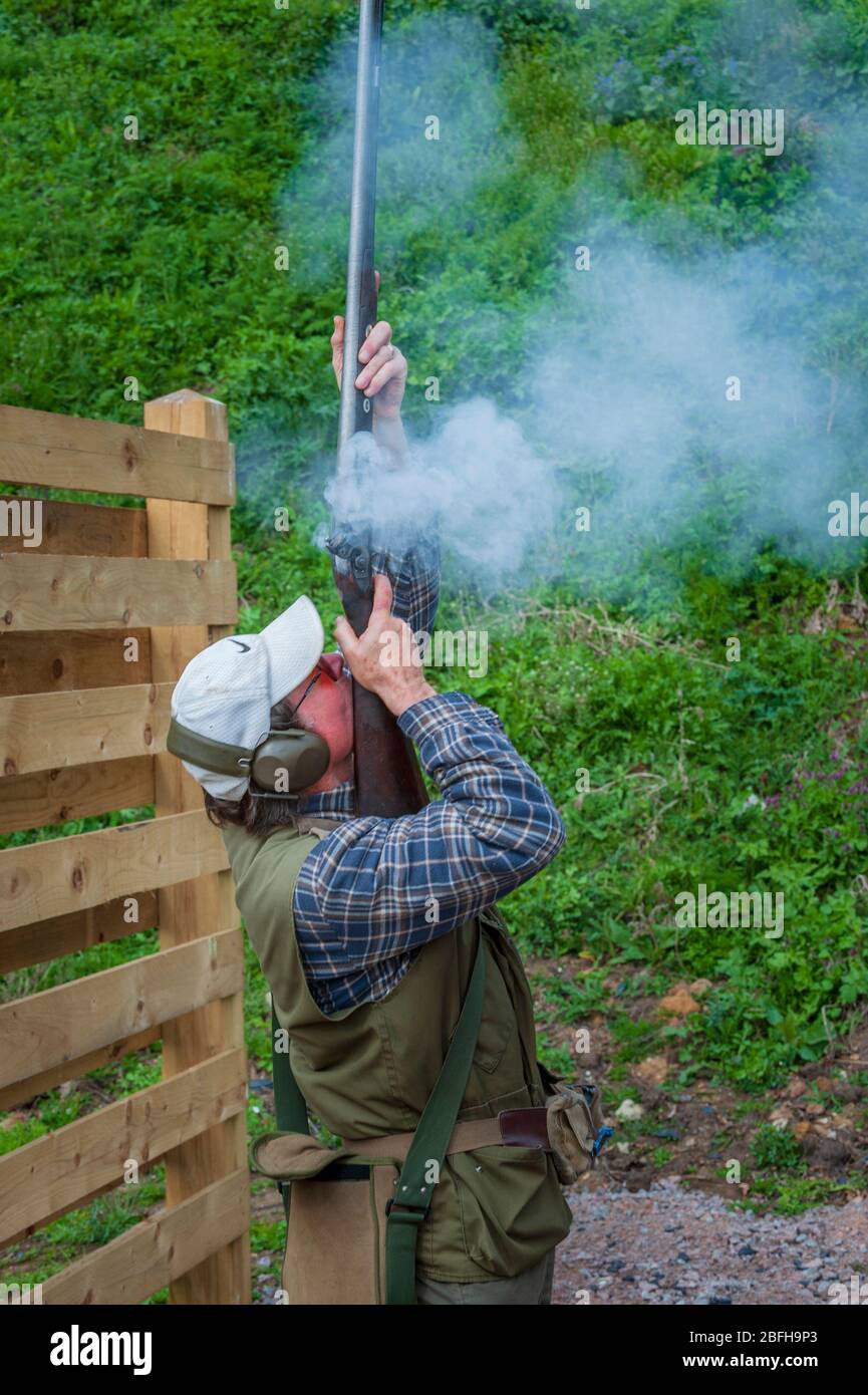 Ein antikes Feuerstein-Schlossgewehr, das von einem Mann während eines Tontaubenschießwettbewerbs abgefeuert wird Stockfoto