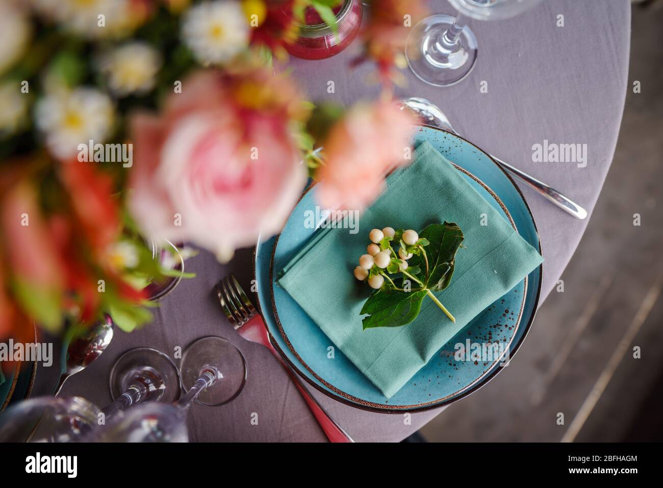 Keramikplatten und anderes Besteck sind auf einem Holztisch mit weichen Tischdecken für ein luxuriöses Mittagessen angeordnet. Stockfoto