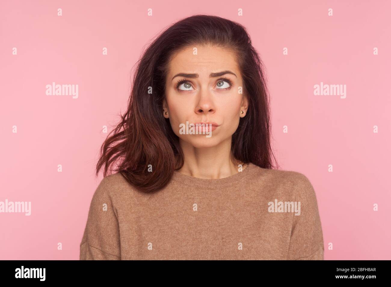 Porträt von peinlich lustige junge Frau mit Brünette Haar machen dumm komische Gesicht mit Augen gekreuzt, denken intensiv suchen dumm und verwirrt. In Stockfoto