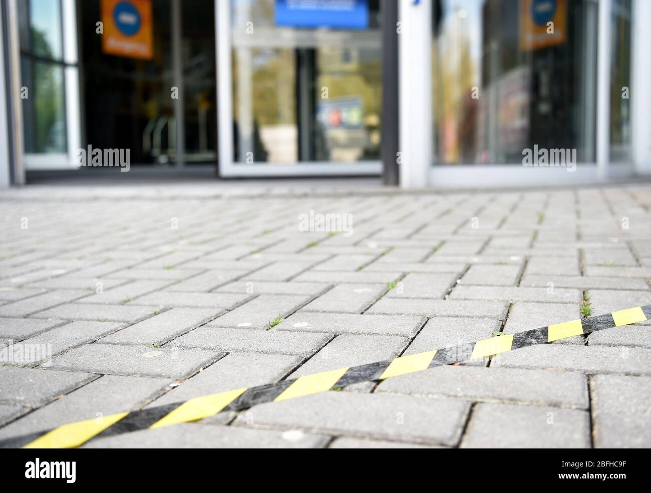 Bochum, Deutschland. April 2020. Ein Klebestreifen auf dem Boden vor dem Eingang zum Möbelhaus Hardeck markiert die Distanz für die Kunden. Nach der langen Pause durch die Corona-Pandemie werden viele Filialen in NRW auf die Wiedereröffnung vorbereitet. Ab Montag können Geschäfte mit einer Verkaufsfläche von bis zu 800 Quadratmetern sowie Möbelgeschäfte wieder eröffnet werden. Quelle: Caroline Seidel/dpa/Alamy Live News Stockfoto