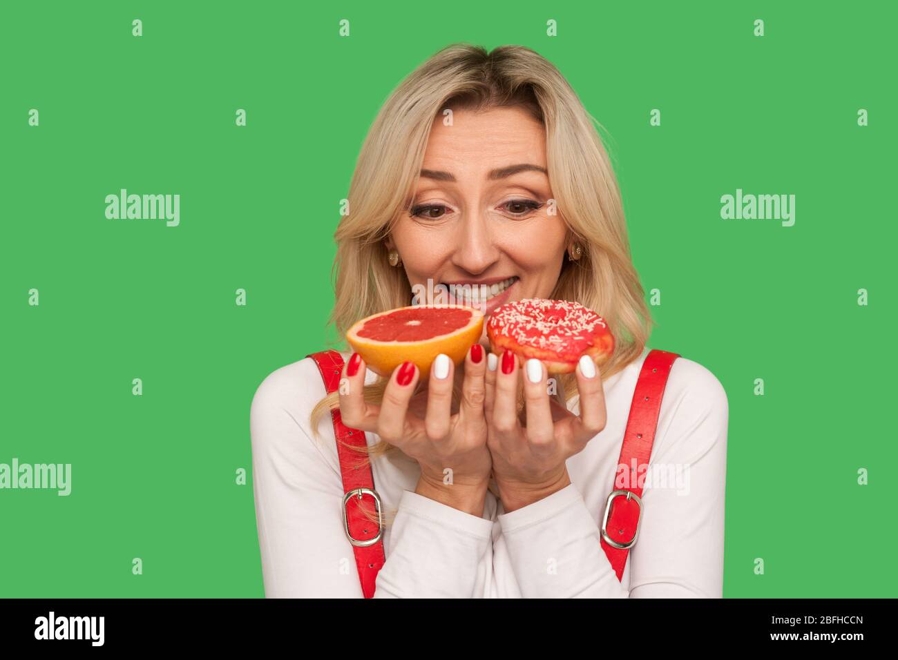 Nahaufnahme von aufgeregt freudige Erwachsene Frau Blick auf Grapefruit und Donut mit großem Glück, mit großen Wunsch, köstliche zuckersüße Lebensmittel zu essen. ich Stockfoto