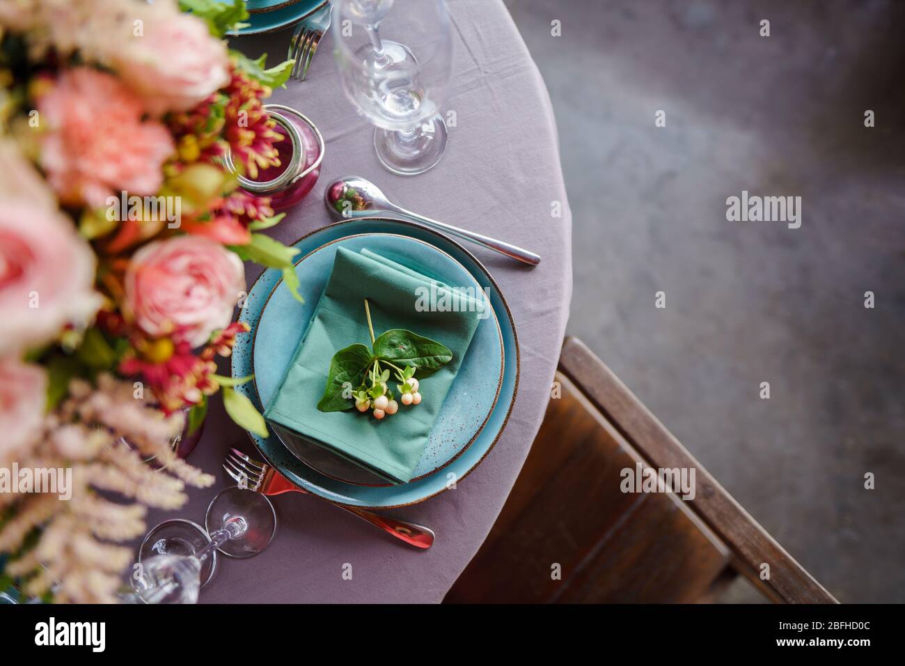 Keramikplatten und anderes Besteck sind auf einem Holztisch mit weichen Tischdecken für ein luxuriöses Mittagessen angeordnet. Stockfoto