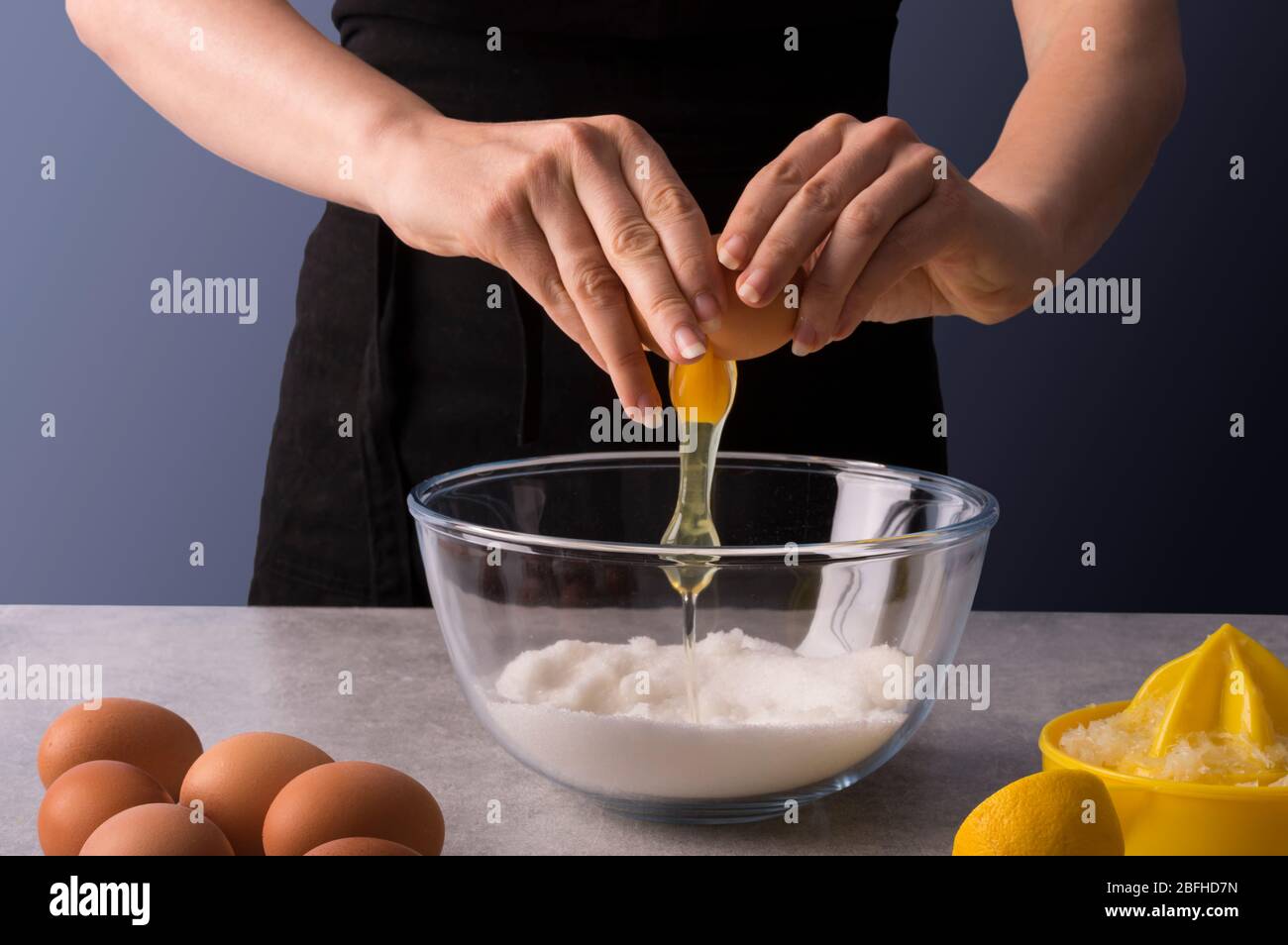 Weibliche Bäckerhände machen Teig für hausgemachte süße Brot. Frische und trockene Zutaten von Zitronen und Orangen auf steingrauem Tisch. Kochkurse oder r Stockfoto