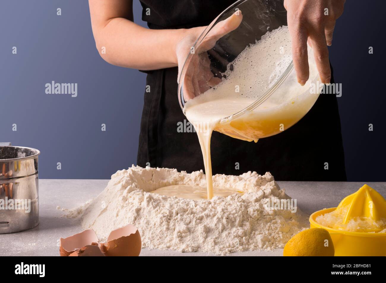 Weibliche Bäckerhände machen Teig für ein hausgemachtes süßes Brot. Frische und trockene Zutaten von Zitronen und Orangen auf steingrauem Tisch. Kochkurse oder r Stockfoto