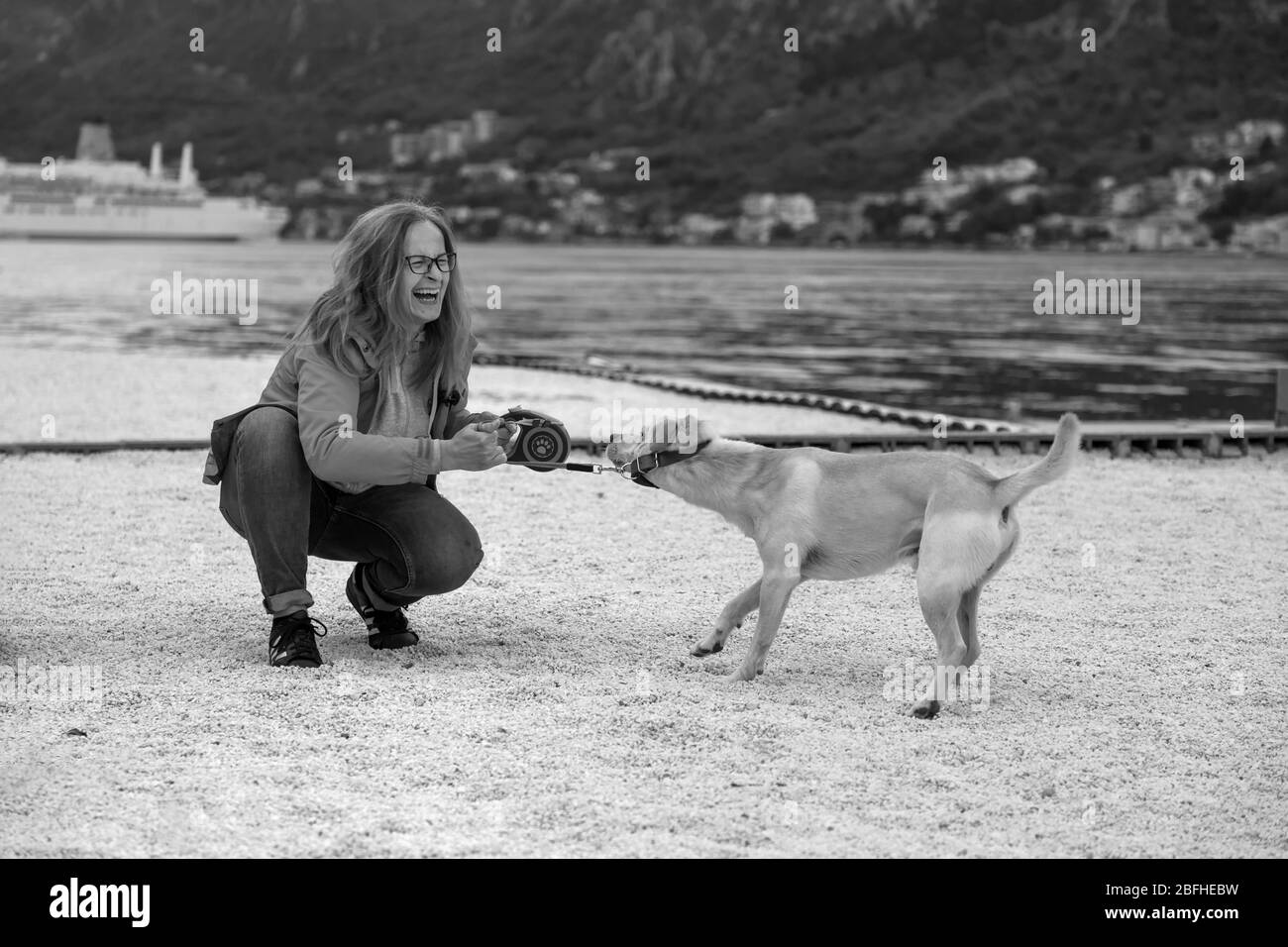 Dobrota, Montenegro, 1. Mai 2019: Eine Frau, die lacht und mit ihrem Hund spielt Stockfoto