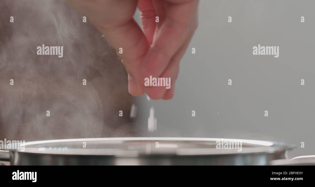 Mann Hände salzen kochendes Wasser in Topf Nahaufnahme Stockfoto