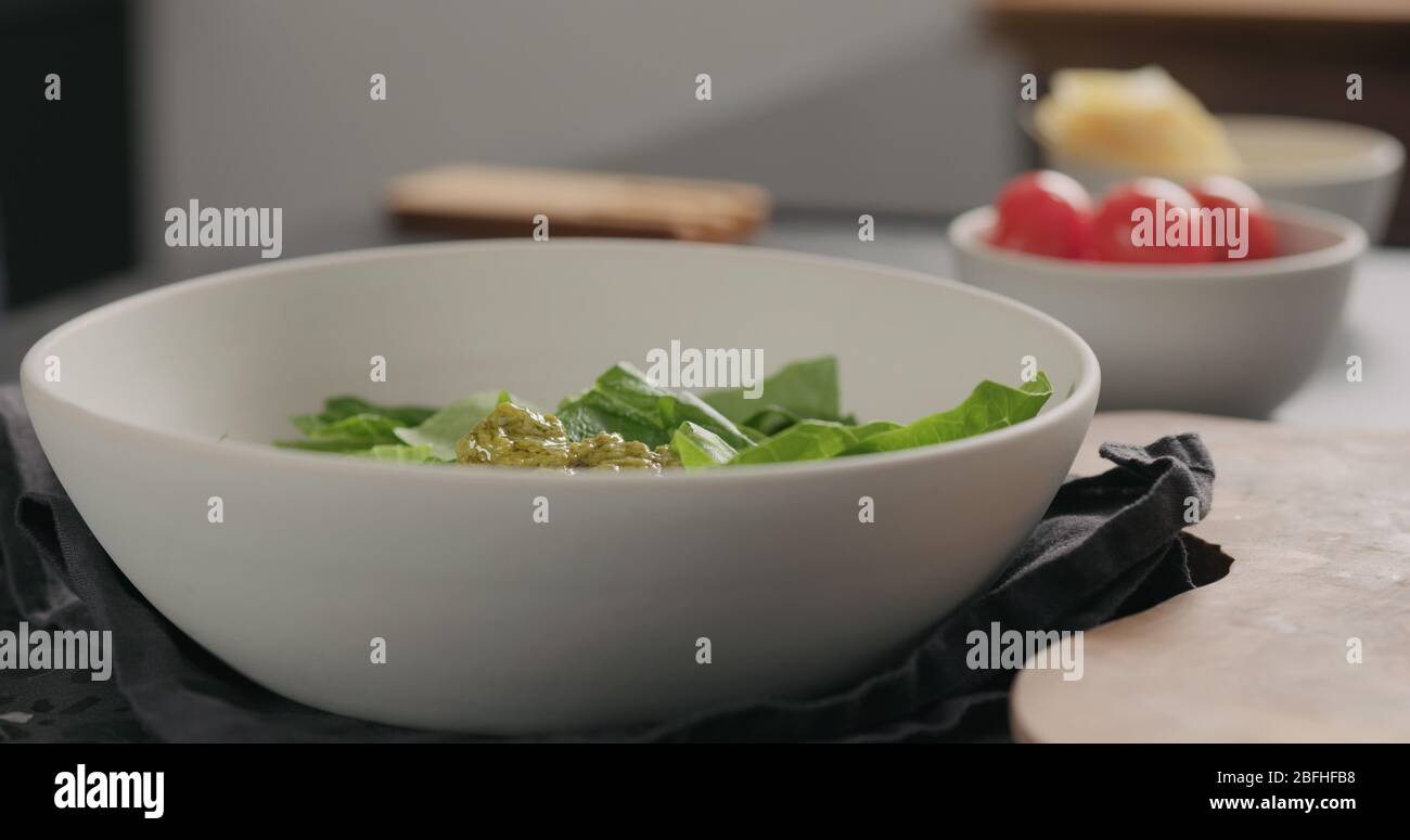 Pesto über Rosensalat in eine weiße Schüssel geben Stockfoto