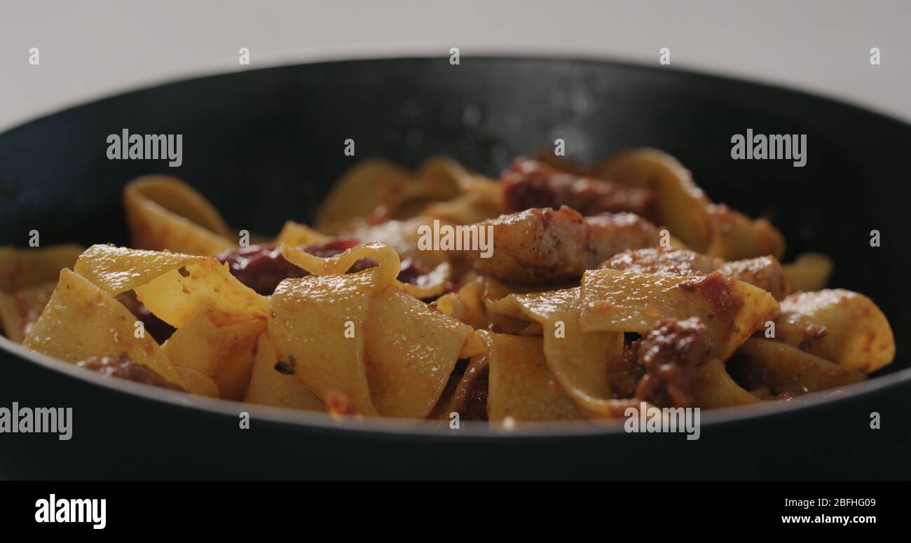 Tagliatelle Pasta mit Huhn, roter Pesto-Sauce und sonnengetrockneten Tomaten in schwarze Schüssel Nahaufnahme Stockfoto