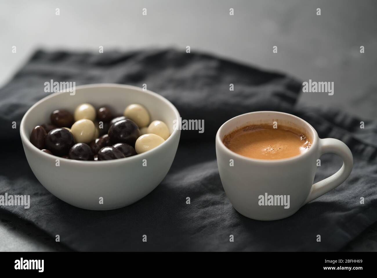 Heißer Espresso in weißer Tasse und Schokodragee auf Leinen Tuch mit Kopierplatz Stockfoto