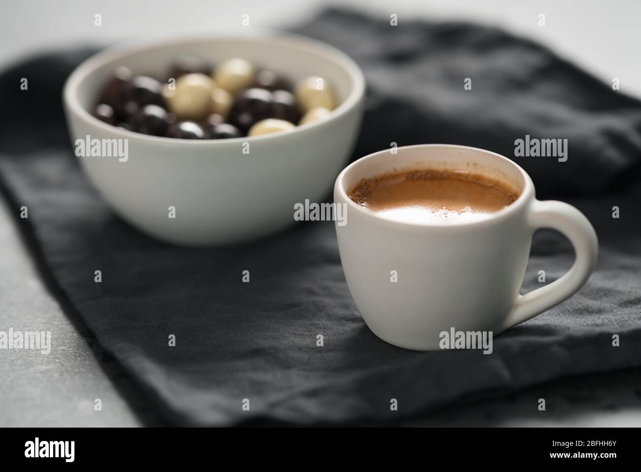 Heißer Espresso in weißer Tasse und Schokodragee auf Leinen Tuch mit Kopierplatz Stockfoto