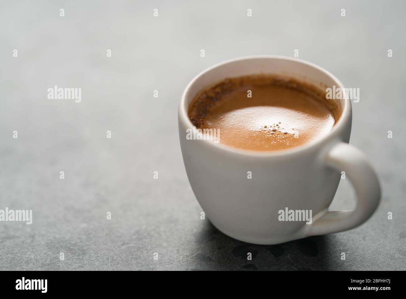 Heißer Espresso in weißer Tasse auf betontem Hintergrund mit Kopie Platz Stockfoto