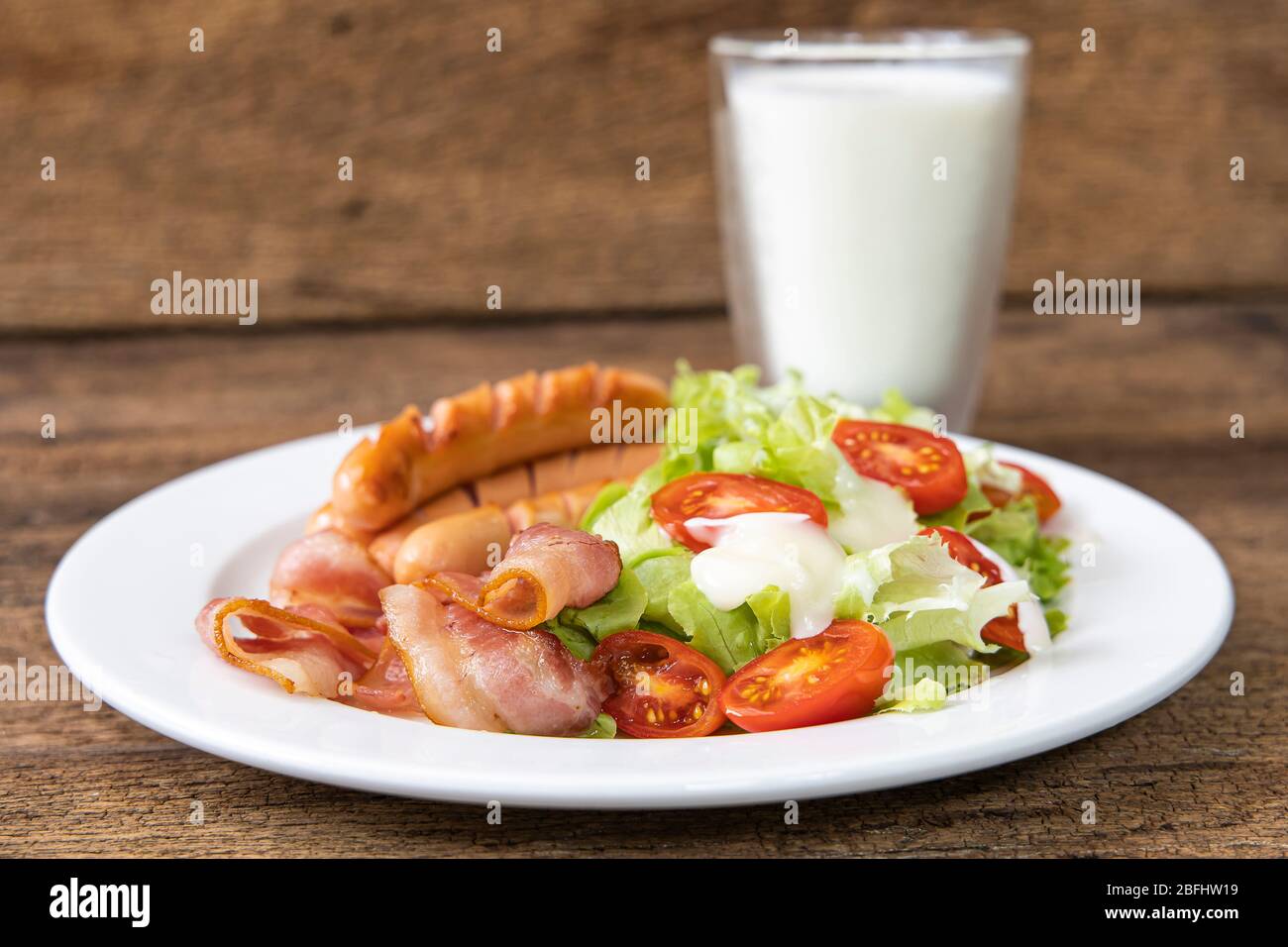 Close-up Speck, Wurst, Salat mit Milch auf Holztisch Hintergrund. Stockfoto