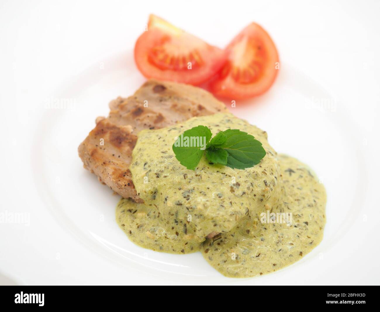 London, 2020, gebratene Thunfischsteak serviert mit EINER cremigen Basilikum-Pesto-Sauce, frischer Minze und Bio-Tomaten. Stockfoto