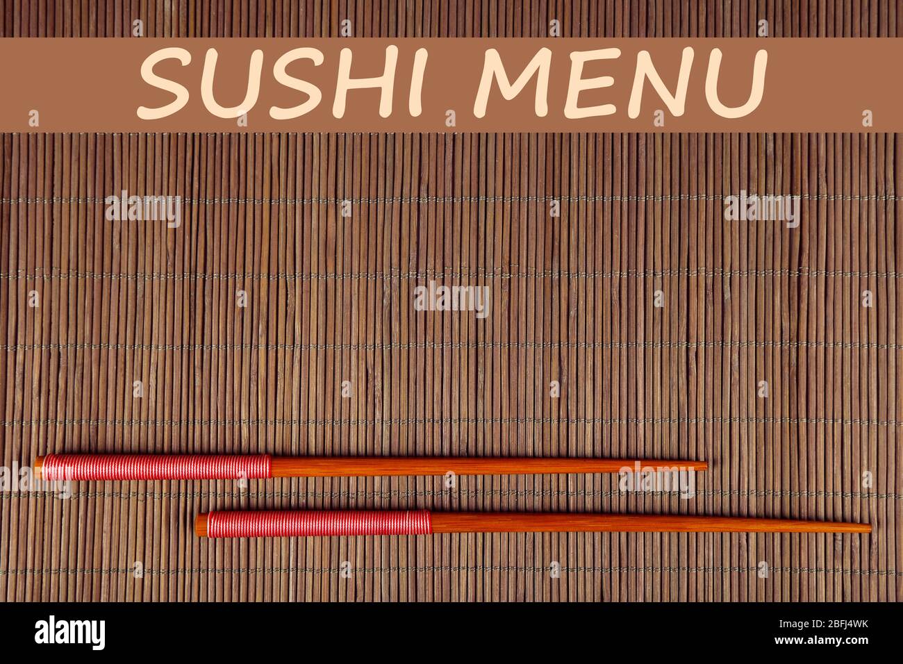 Paar Essstäbchen und Sushi-Menü Text auf braunem Bambus-Matte Hintergrund Stockfoto