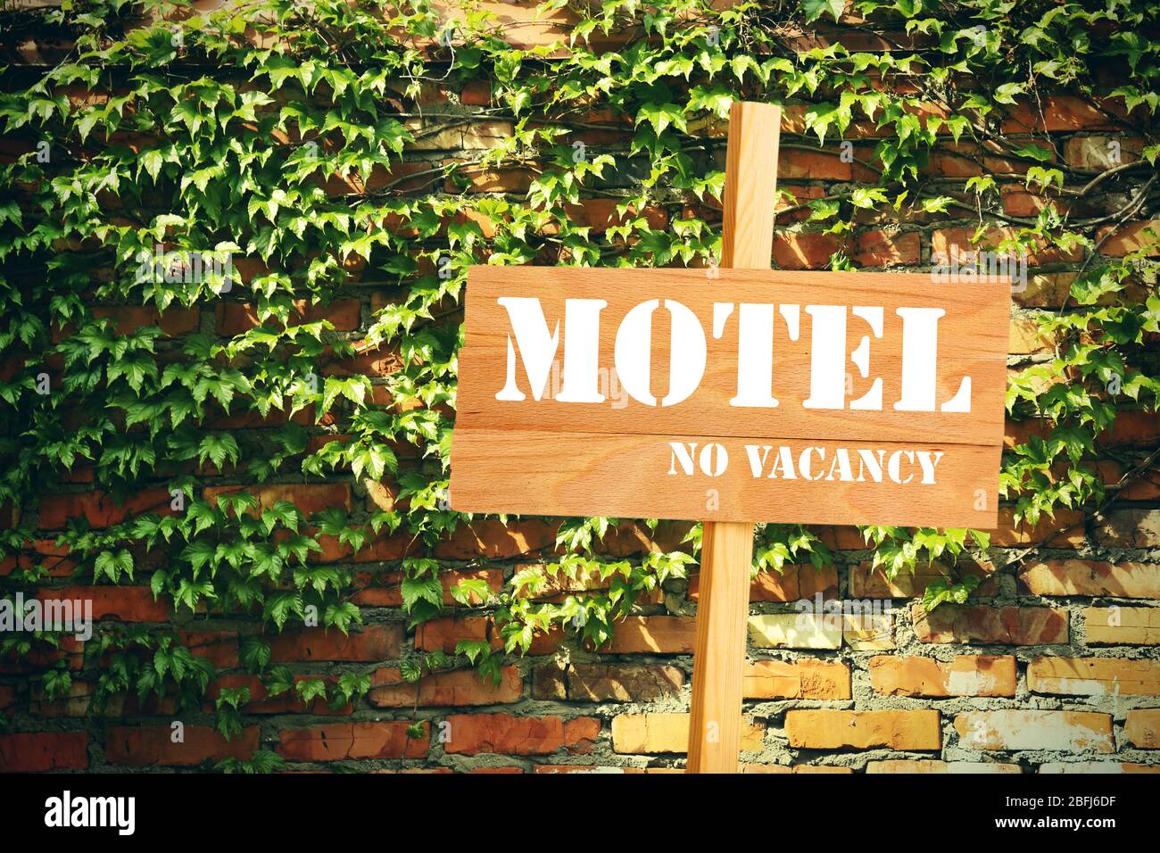 Schild mit Text Motel, No Vacancy in der Nähe des Hotels auf Backsteinmauer Hintergrund Stockfoto