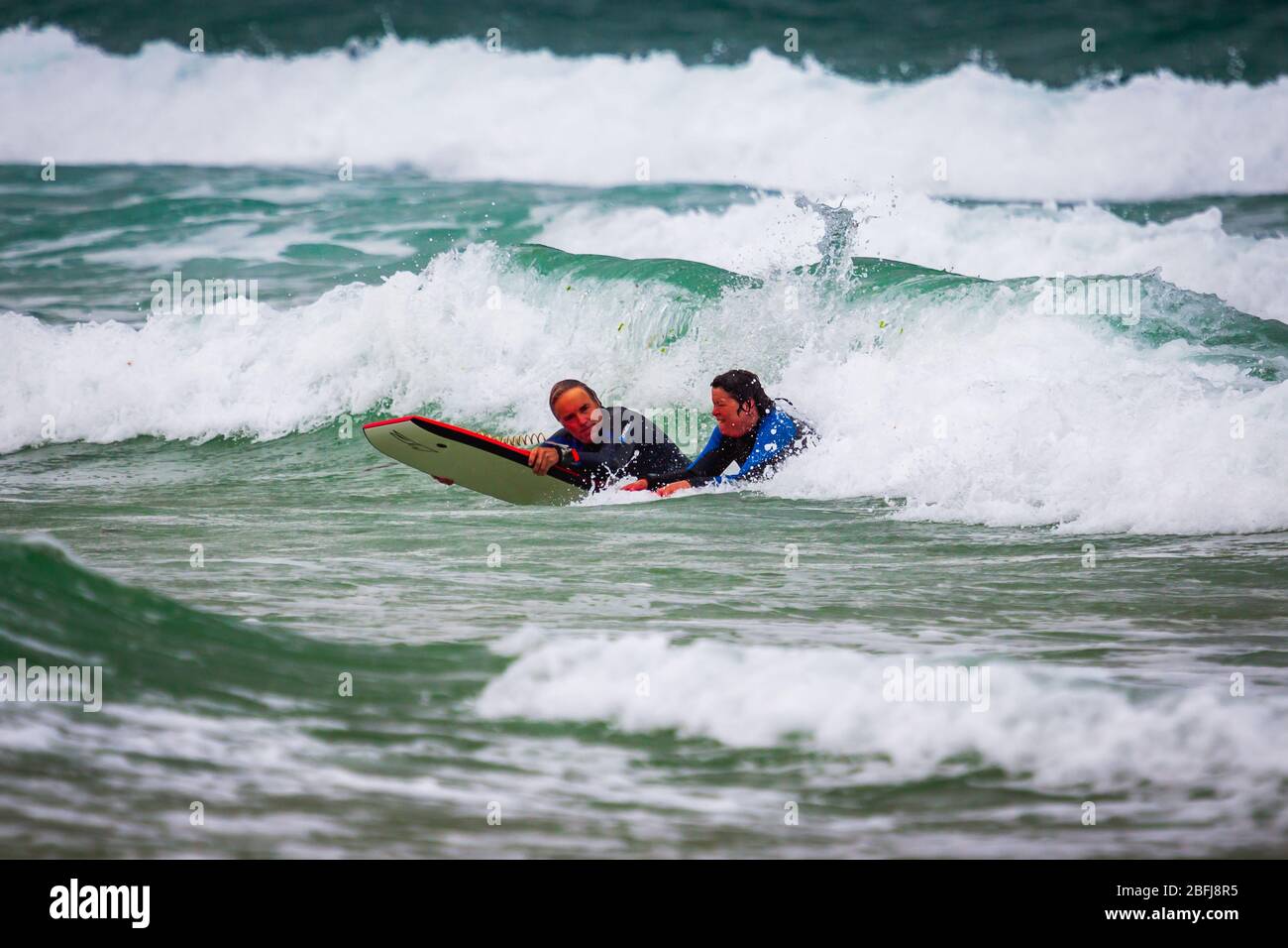 Cornish Surfers genießen das weiße Wasser Stockfoto