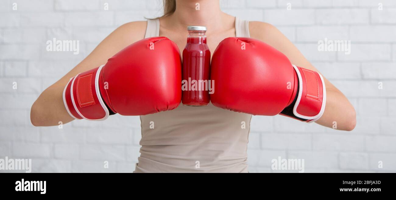Frau in Boxhandschuhen hält rote Detox Smoothie Stockfoto