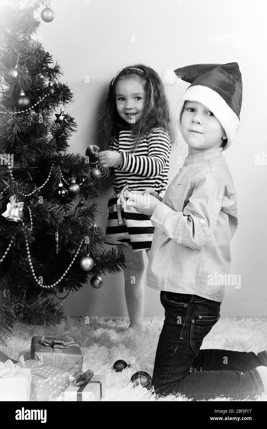 Kinder schmücken Weihnachtsbaum mit Kugeln im Zimmer Stockfoto