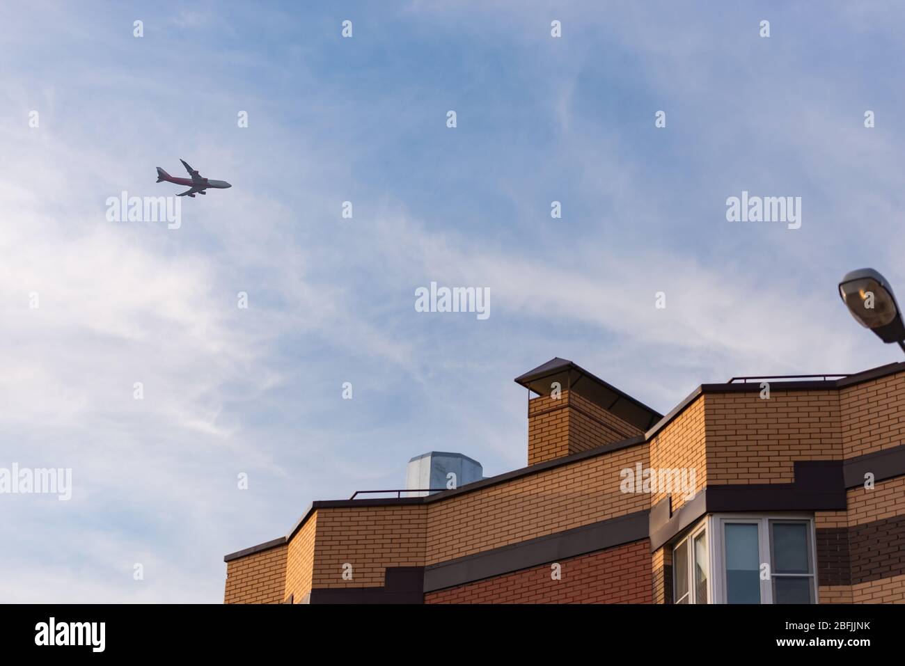 Das Flugzeug über dem Appartementblock. Glissada geht über Hochhäuser. Lärm von Flugzeugen verhindert den Schlaf Stockfoto