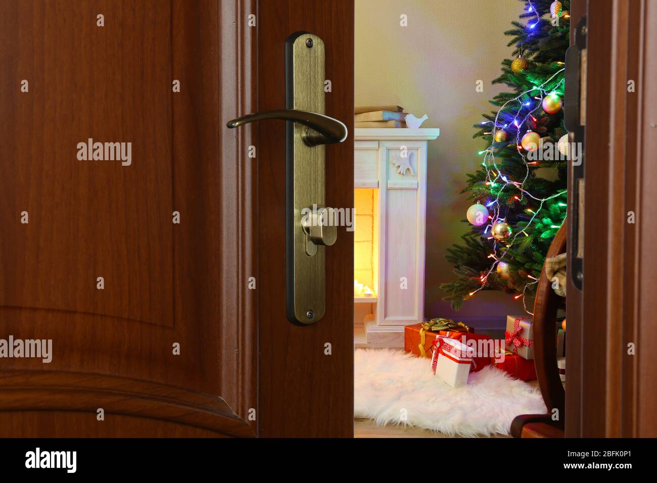Offene Tür mit geschmücktem Weihnachtsbaum im Zimmer Stockfoto