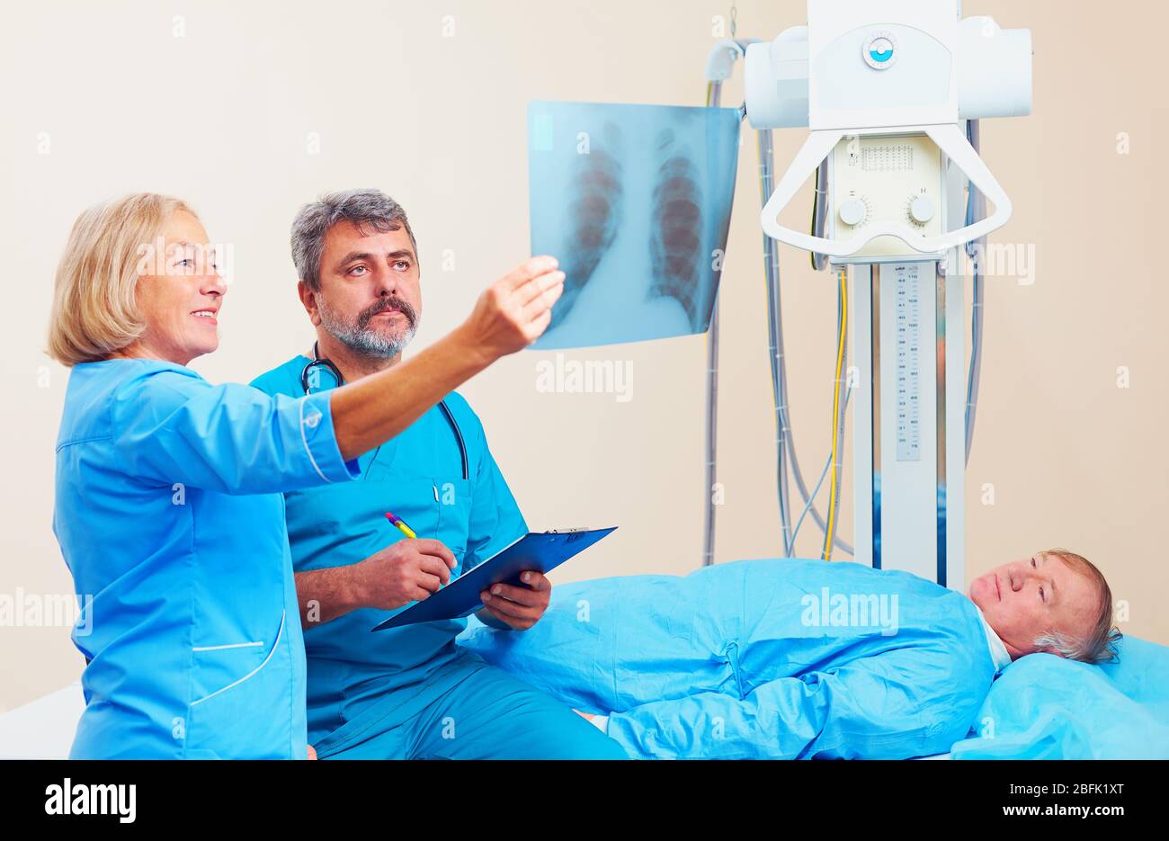 Ärzte besprechen das Röntgenbild im Röntgenraum mit dem Patienten Stockfoto